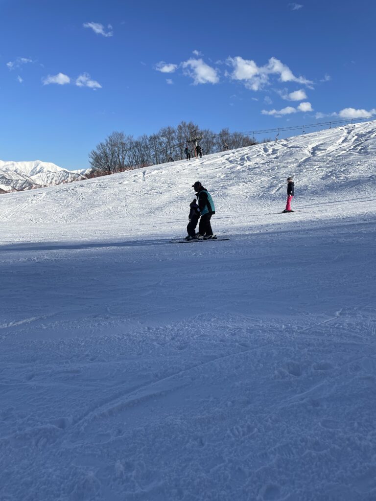 青空の下のゲレンデを滑るスキーヤー