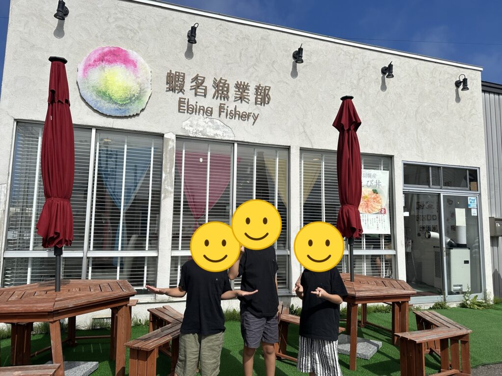 蝦名漁業部の外観の前に立つ子どもたち