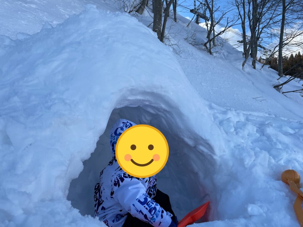 雪のかまくらの中で遊ぶ子ども