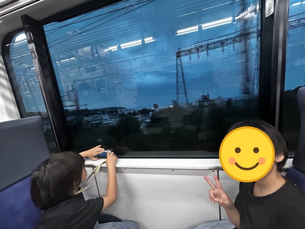 電車の窓から外を眺める子どもたち
