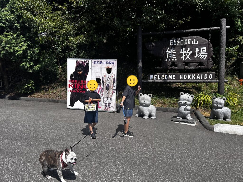昭和新山熊牧場の看板の前で立つ子どもたち(顔はスタンプで加工)