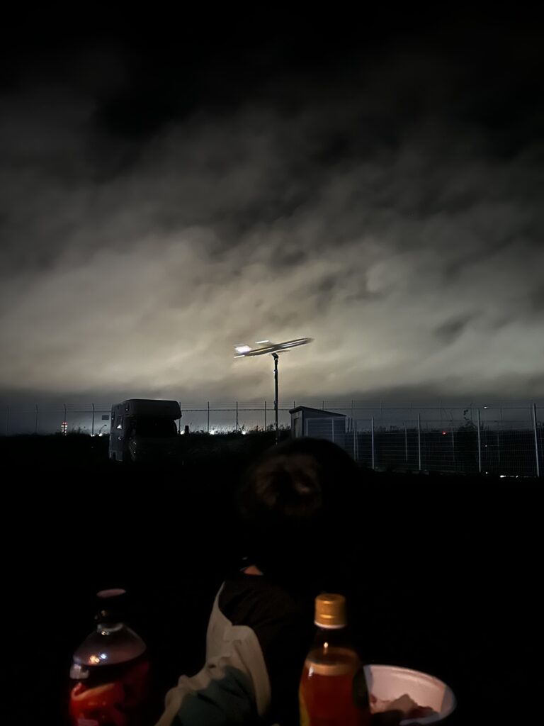 滑走路の上空を飛ぶ飛行機を眺める夜空