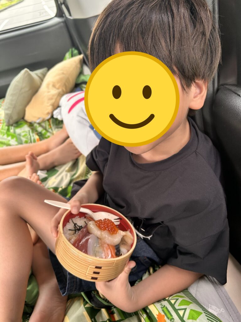 車内で朝弁の海鮮丼を食べる子ども(顔はスタンプで加工)