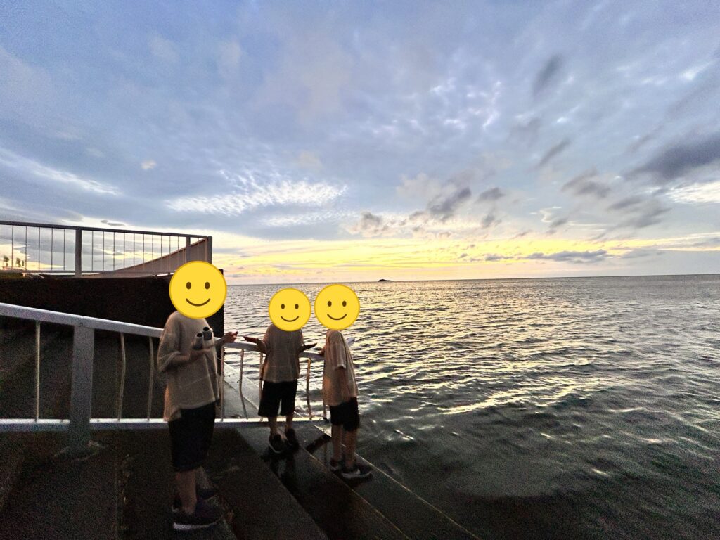 夕日が沈む海を眺める子どもたち