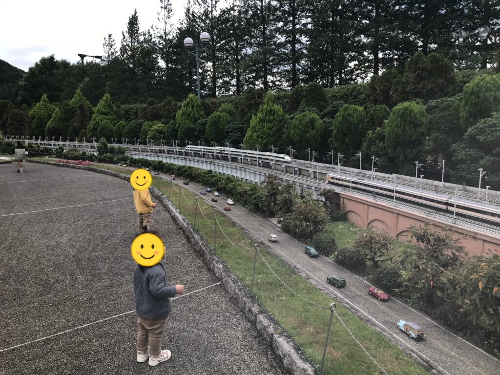 ミニチュアの新幹線と高速道路を見る子どもたち
