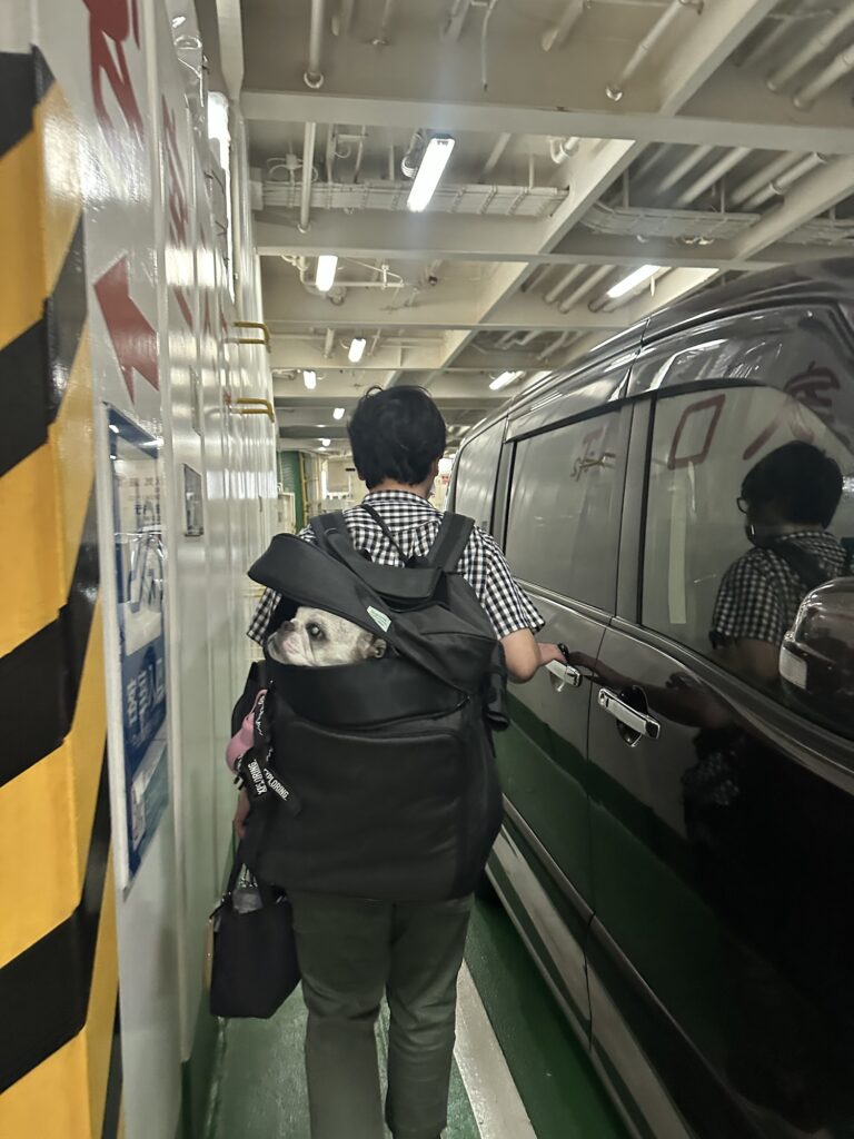 リュックにワンコを入れて車からおりる家族