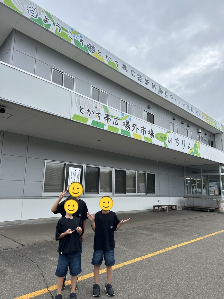 とかち帯広場外市場の建物の前に並ぶ三兄弟(顔はスタンプで加工)