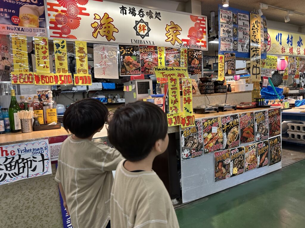 市場のお店を見上げる子どもたちの後ろ姿